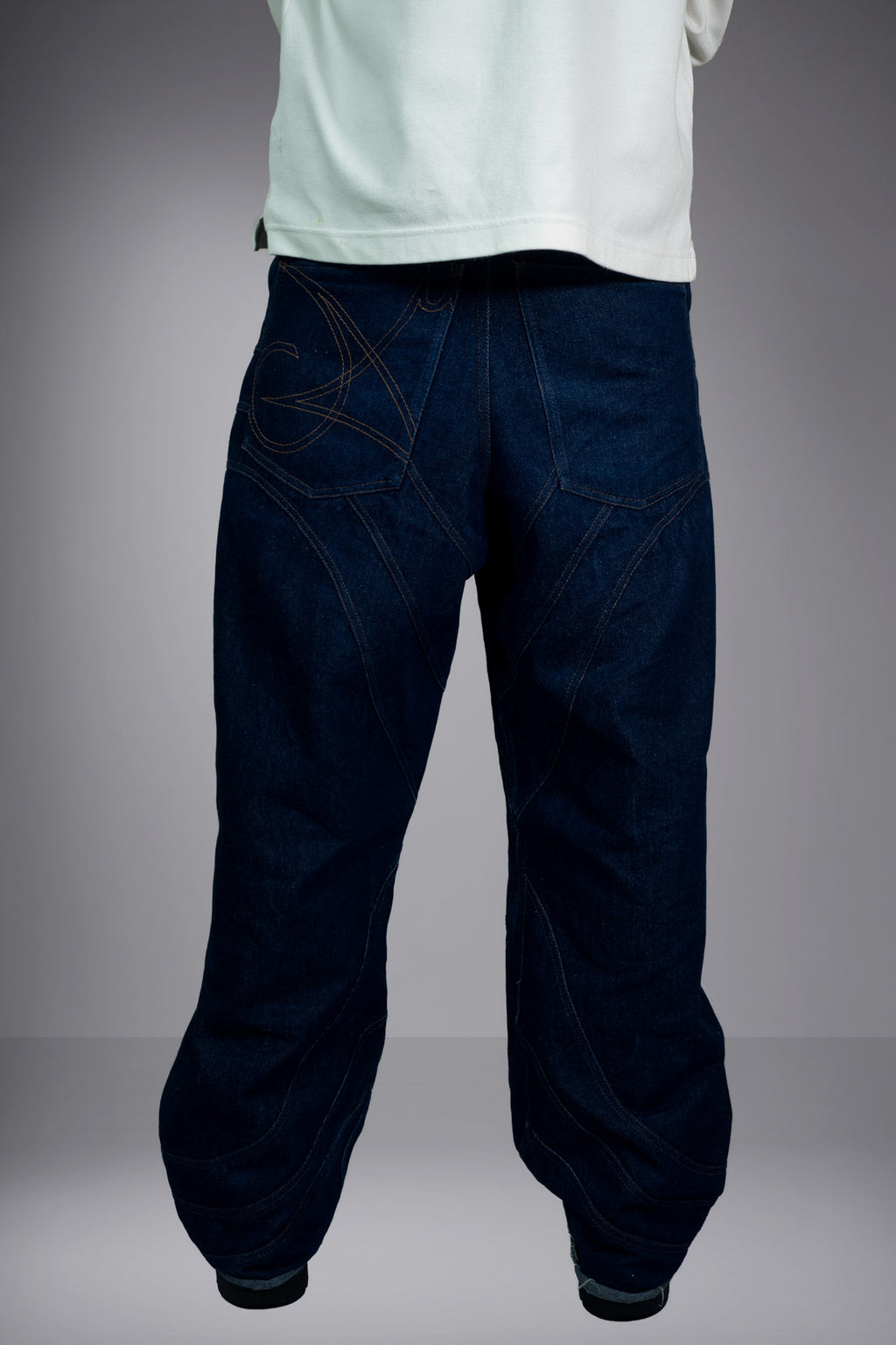 Back view of dark raw denim baggy jeans with patch pockets and graphic seam details. - Motor Cycle Brut