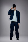 Full-body front view of a dark raw denim jacket worn open with matching wide baggy jeans and contrast stitching. - Motor Cycle Brut