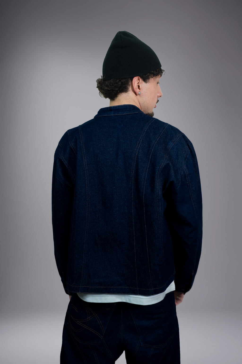 Back view of a dark raw denim jacket with contrast stitching, worn with matching baggy jeans - Motor Cycle Brut