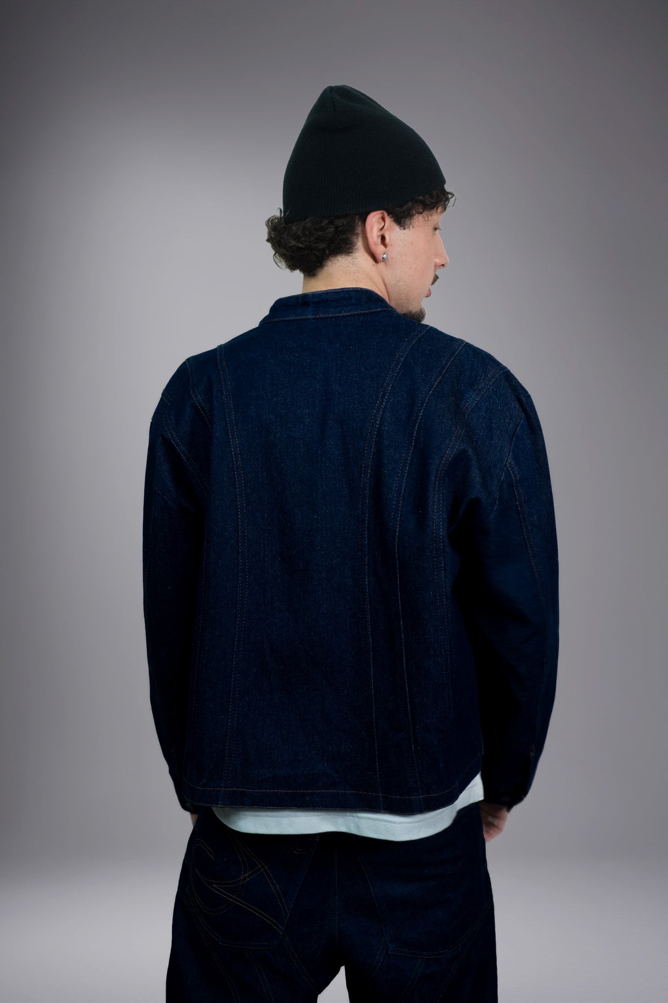 Back view of a dark raw denim jacket with contrast stitching, worn with matching baggy jeans - Motor Cycle Brut
