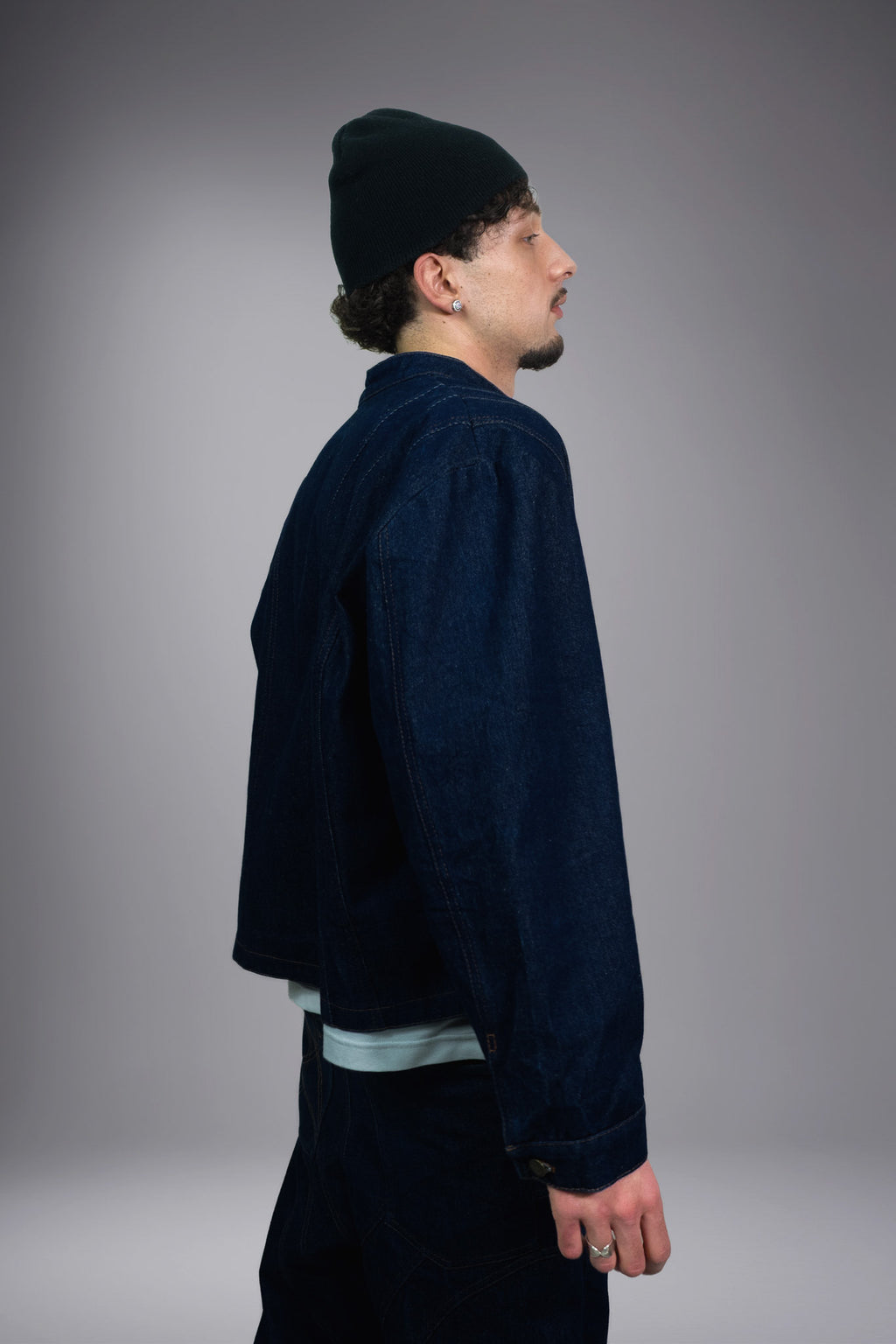 Side view of a dark raw denim jacket with wide sleeves, contrast stitching and a cropped fit - Motor Cycle Brut