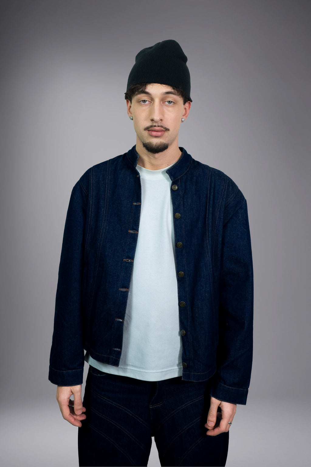 Front view of a dark raw denim jacket worn open with matching baggy jeans and contrast stitching. -  Motor Cycle Brut