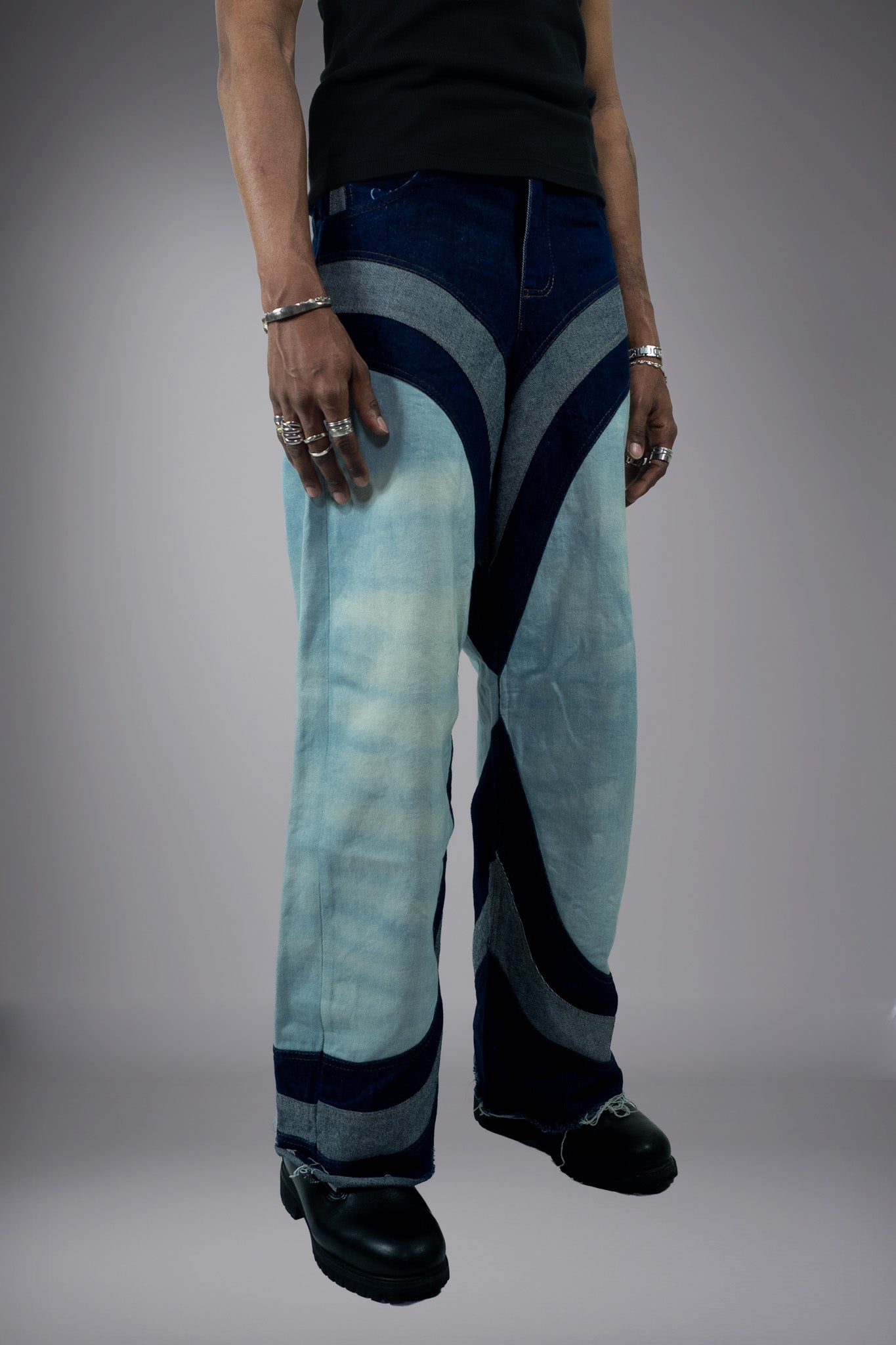 Front close-up of two-tone wide-leg denim jeans with light wash panels, dark curved inserts, contrast stitching and raw hem details. - Motor Cycle Triple Jean