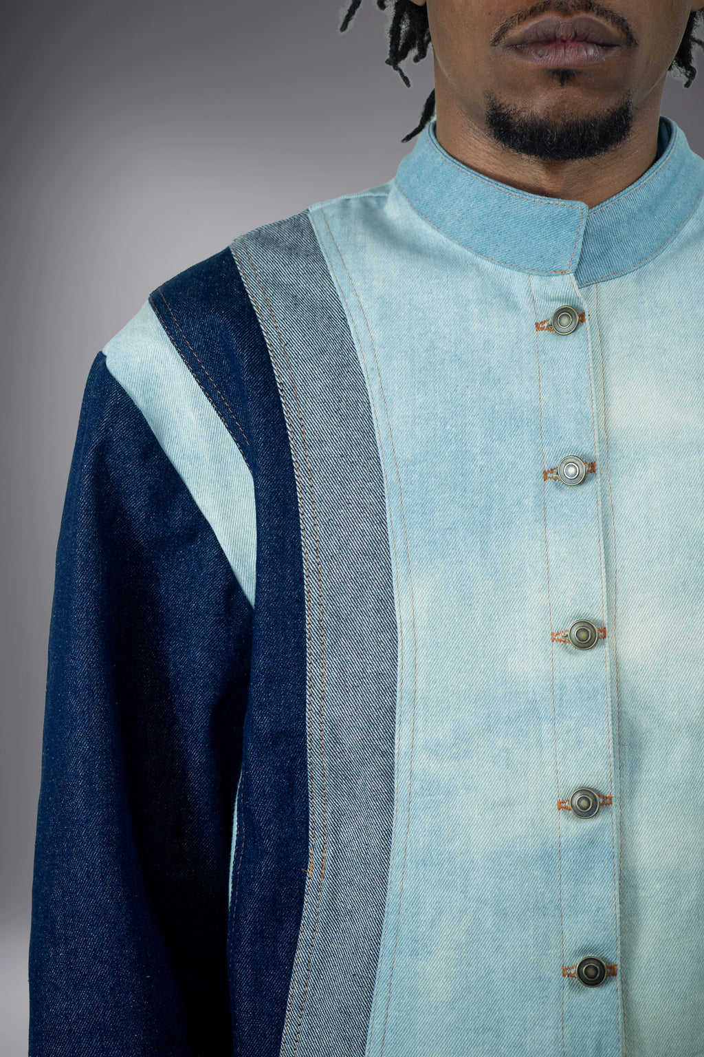Close-up of a two-tone denim jacket with light wash panels, dark denim sleeves, contrast stitching and button closure. - Motor Cycle Triple Jean