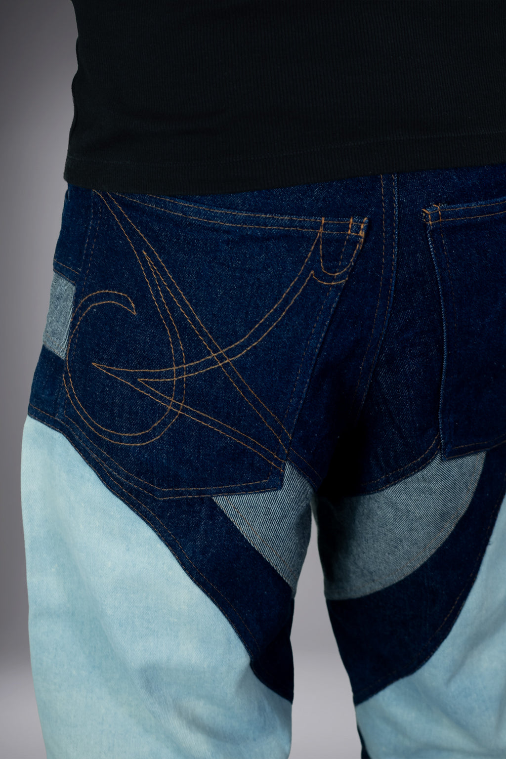 Close-up back detail of two-tone denim jeans with dark blue pockets, graphic contrast stitching and curved light wash panels. - Motor Cycle Triple Jean