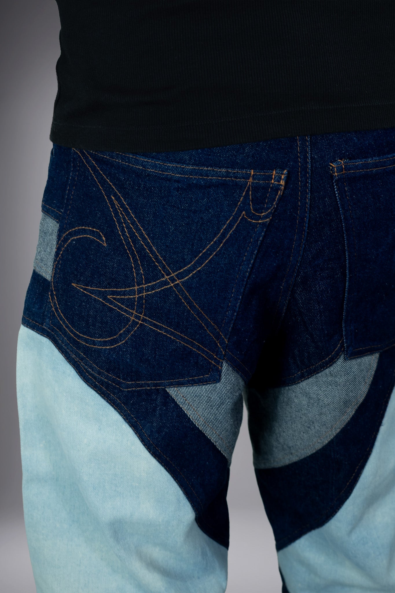 Close-up back detail of two-tone denim jeans with dark blue pockets, graphic contrast stitching and curved light wash panels. - Motor Cycle Triple Jean
