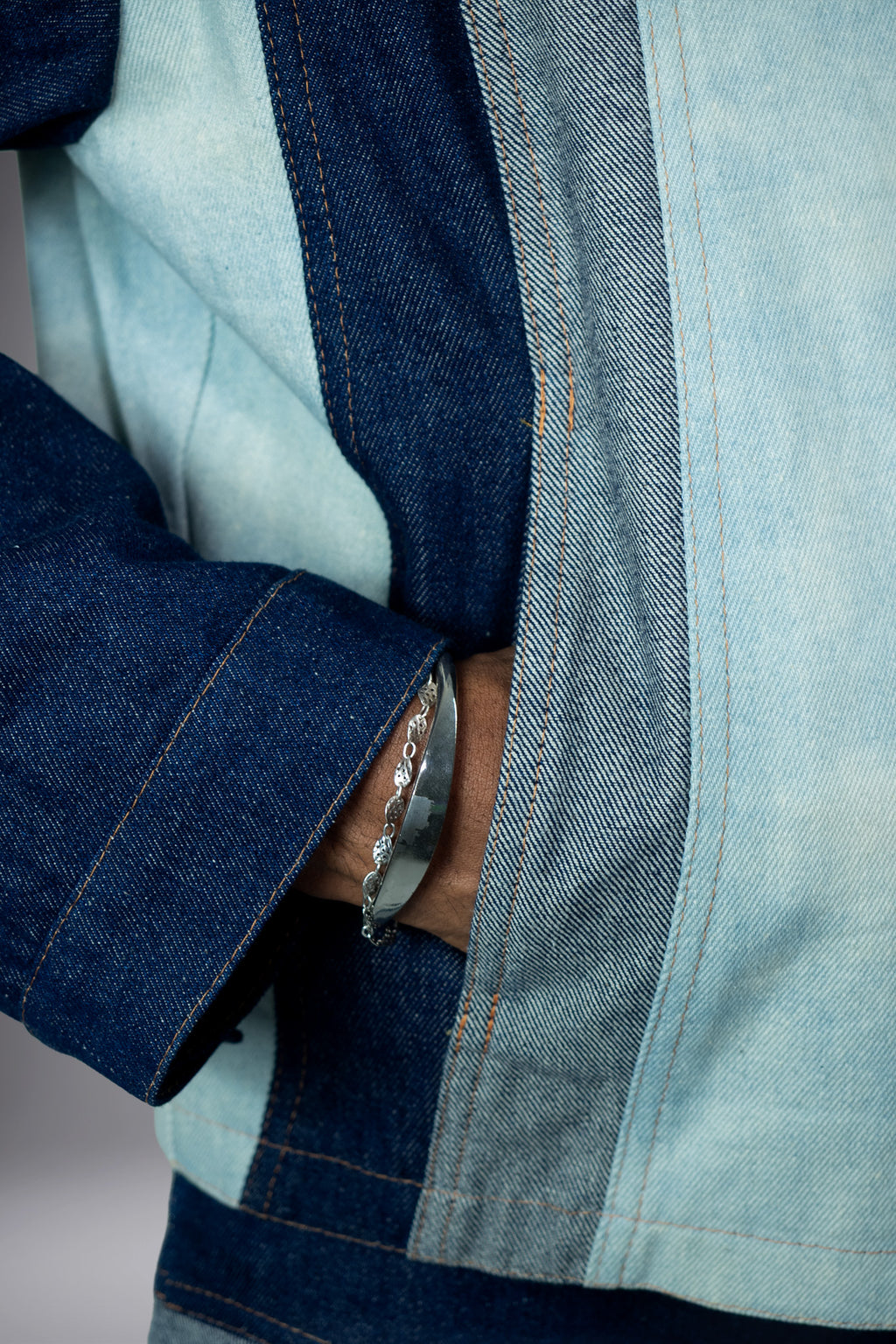 Close-up of a two-tone denim jacket with dark blue sleeve, light wash body panels, contrast stitching and side pocket detail. - Motor Cycle Triple Jean