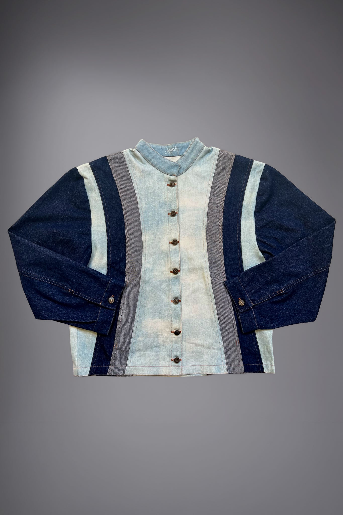 lat lay of a two-tone denim jacket with light wash body panels, dark denim sleeves, grey side inserts, metal buttons and contrast stitching. - Motor Cycle Triple Jean