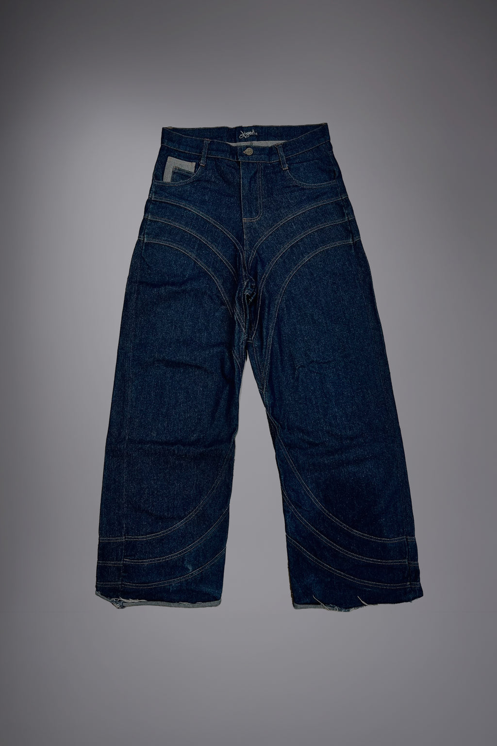 Flat lay of dark raw denim baggy jeans with curved contrast stitching and wide-leg construction - Motor Cycle Brut